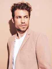 Closeup portrait of handsome confident stylish hipster lambersexual model. Sexy modern man dressed in elegant beige suit. Fashion male with curly hairstyle posing in studio. Isolated