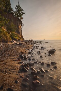 Beautiful morning seaside landscape. Cliff with stones in water on the Baltic Sea in Gdynia, Poland. Photo with the effect of a long exposure.