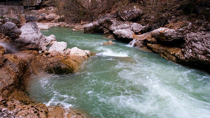 The mouth of a rocky mountain river flows. Strong current and seething water, waterfall. The concept of tourism, hiking, wildlife beauty. 