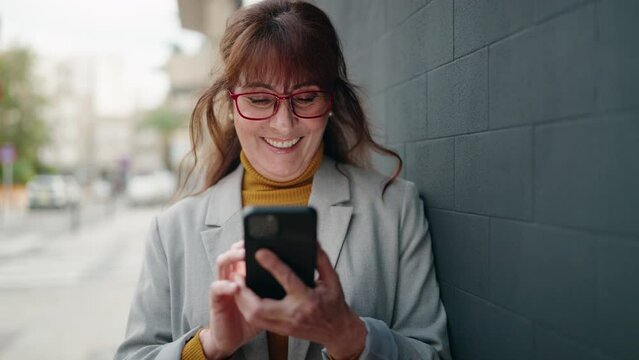 Middle age woman business executive using smartphone at street