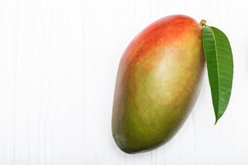 Healthy food red mango fruit has leaf on white table background.