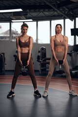 Fototapeta na wymiar Pretty women working out in a gym. Adult ladies with beautiful shaped bodies.