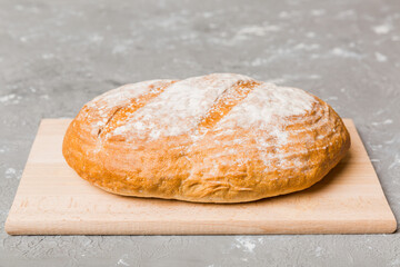 Freshly baked bread on cutting board against white wooden background. perspective view bread with copy space