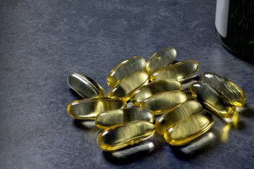 A small heap of fish oil capsules, rich in omega 3,  on a dark background. Cope space.