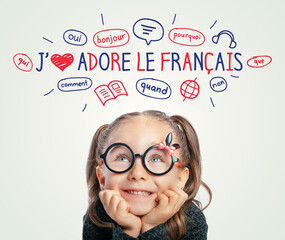 Beautiful cute little girl with eyeglasses looking at I Love French text and illustrations....