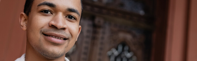 Obraz premium pleased and young african american man looking at camera, banner.