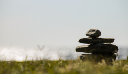 A pile of stones in a field with the sea in the background. Relax
