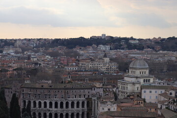 ROME, ITALY - February 05, 2022: Panoramic view around the Colosseum in city of Rome, Italy. Cold and gray sky in the background. Macro photography of the green parks with the old buildings.