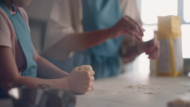 preschooler child is learning to cook in home kitchen or culinary master class in school, little girl is kneading dough