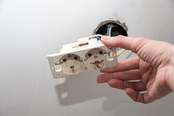 Installation of new electrical wiring, plastic socket and electric wires for future sockets on a plastered wall. Hand installing a new socket. DIY house renovation concept.