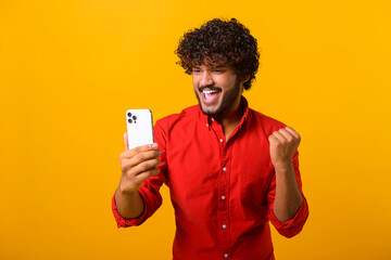 Happy satisfied man with beard holding smartphone and smiling making yes gesture, celebrating...