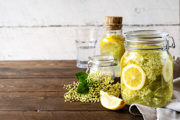 Elderberry infused water or syrup made with fresh flowers and lemons. Copy space. Wooden background