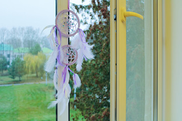 gentle dream catcher with threads and beads hangs on an open window calm weather in the room
