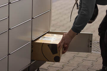 Man receives or sends a box from shopping locker in postal terminal. E-commerce shipping and...