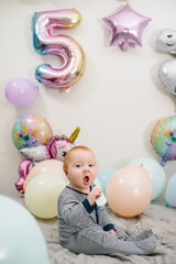 Happy child celebrates her birthday. Party decoration with balloons in the style unicorn, rainbow,...