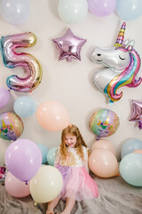 Happy and surprised girl celebrates her birthday. Party decoration with balloons in the style...