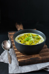 broccoli and green pea soup decorated with sesame seeds and pea sprouts on a dark wood background. tinting. selective focus