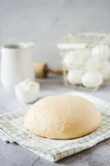 A ball of dough on a white rustic table with flour and a napkin. Homemade dough for pizza or bread.