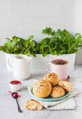 traditional buns with black sesame and berry jam on a background of greenery in a pot. light background, selective focus
