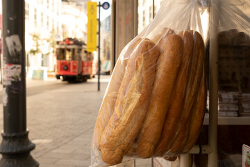 Stale bread in plastic bag on door on background of red retro nostalgic tram in Istiklal street in Istanbul.Concept of food for homeless and poor