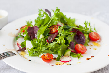 Green salad of fresh lettuce leaves, cherry tomatoes, feta cheese and assorted seeds with a sauce...