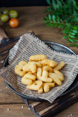 Delicious baked potatoes close-up on an old newspaper in a metal plate on a wooden table