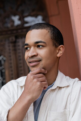 thoughtful african american man in shirt jacket near building in europe.