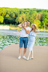 happy young parents mom and dad with their baby son walk in the summer by the water by the sea on the embankment and have fun, smile