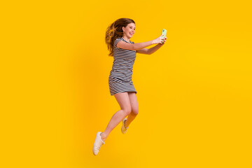 Fototapeta na wymiar Full body profile side photo of young girl shooting selfie mobile jumper isolated over yellow color background