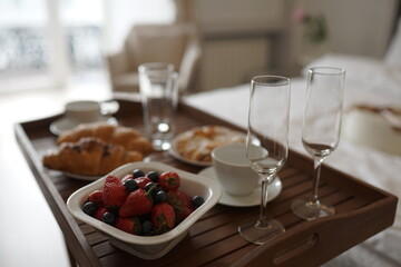 Delicious breakfast in bed. Coffee in bed on a white bed with buns, berries on a white