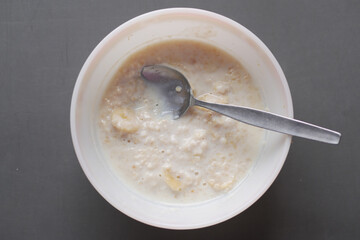 oats, banana and milk in a bowl on black background 