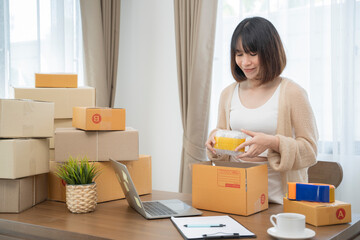 Asian woman packing in boxes to work at home Small Business Owners or Startup Small Business Entrepreneurs working on online marketing shipping boxes.