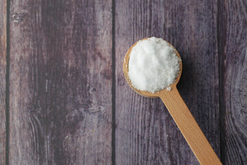 Coarse salt in a wooden spoon on table 