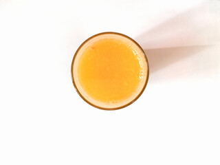 a glass of fresh orange juice on a white background top view