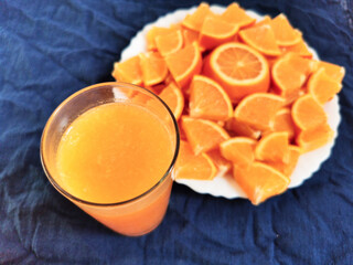 glass of fresh orange juice and a slice of orange on a plate