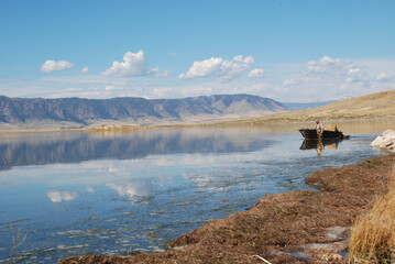 A waterfowl hunter retrieves a boat on a mountain lake. 