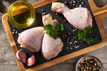 Raw chicken meat legs with spices and herbs on cutting board. Top view