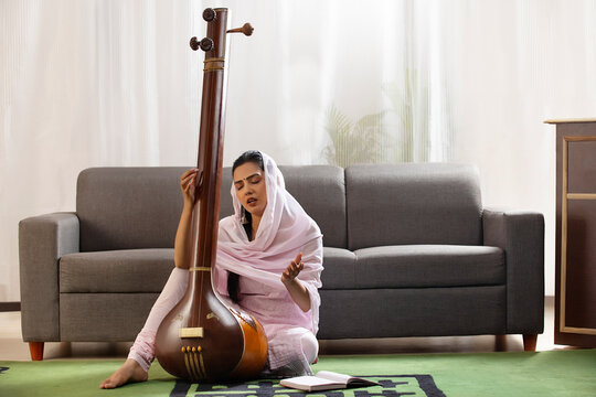 Young female classical singer playing Tanpura at home