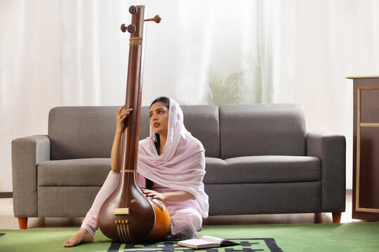 Young female classical singer playing Tanpura at home