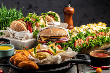 Set of Homemade burgers with grilled meat, vegetables, sauce French fries on rustic wooden background. fast food and junk food concept