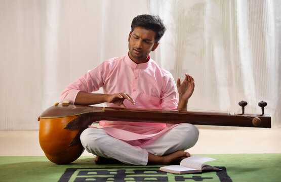 Young male classical singer playing Tanpura at home