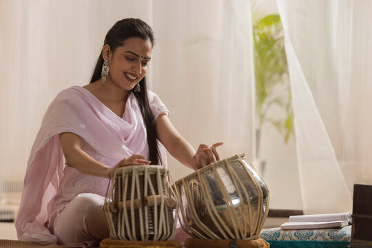 Portrait of young woman playing Tabla at home