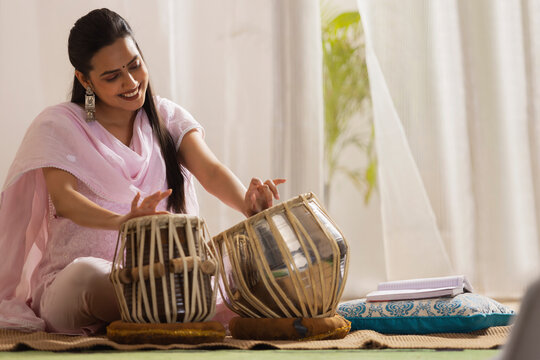 Portrait of young woman playing Tabla at home