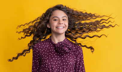 kid smile with long brunette curly hair on yellow background