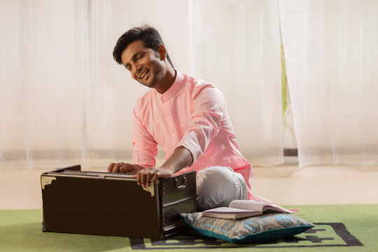 Portrait of young man playing harmonium at home