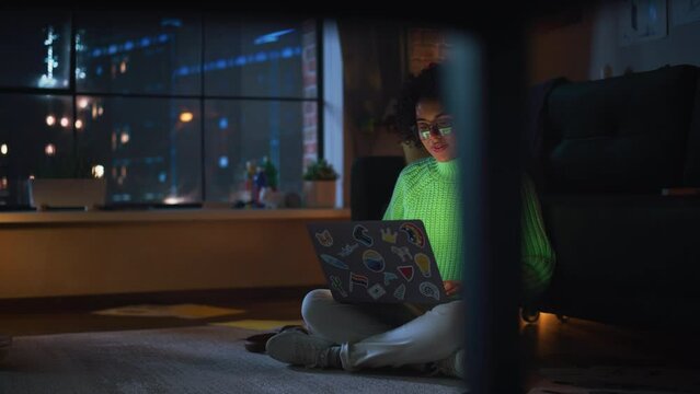 Black Female IT Specialist Coding at her Laptop During the Evening and Check Notification at Smartphone. Diverse Woman have Deadline Late at Night. Millennial People Concept
