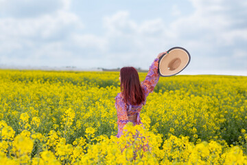 Fototapeta premium Young woman walking through a field of flowers