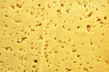 the surface of a cut piece of cheese with holes background backdrop