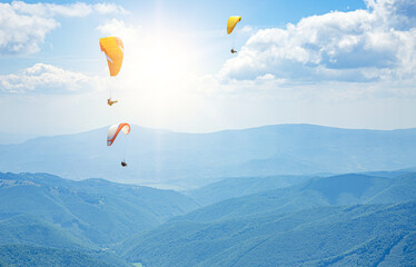 Paragliders in flight against the background of the sky and mountains.