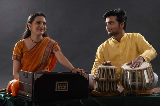 Man and woman performing together with harmonium and Tabla in a classical musical concert